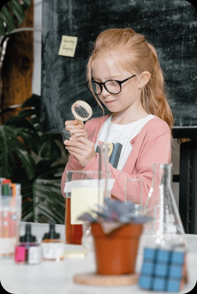 Niña explorando con lupa en actividad de ciencia en educación inicial